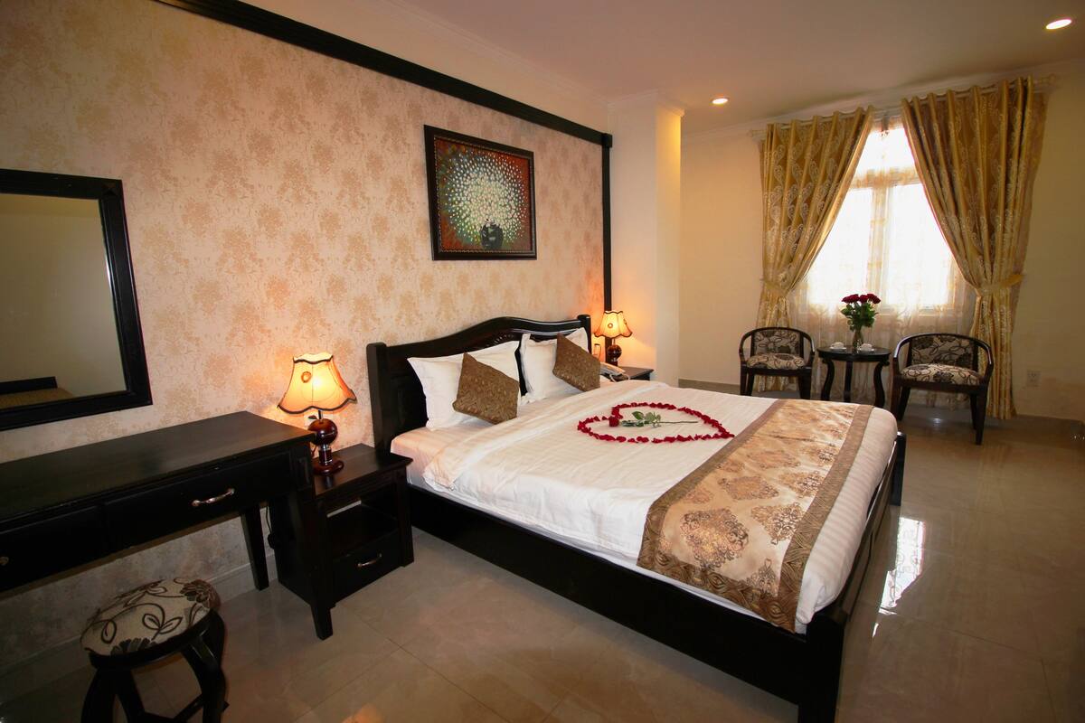 A well-appointed hotel room with a large bed, a nightstand, a desk, and a chair.