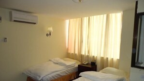 Une chambre avec deux lits simples, une table de chevet avec une lampe et une fenêtre avec des rideaux.