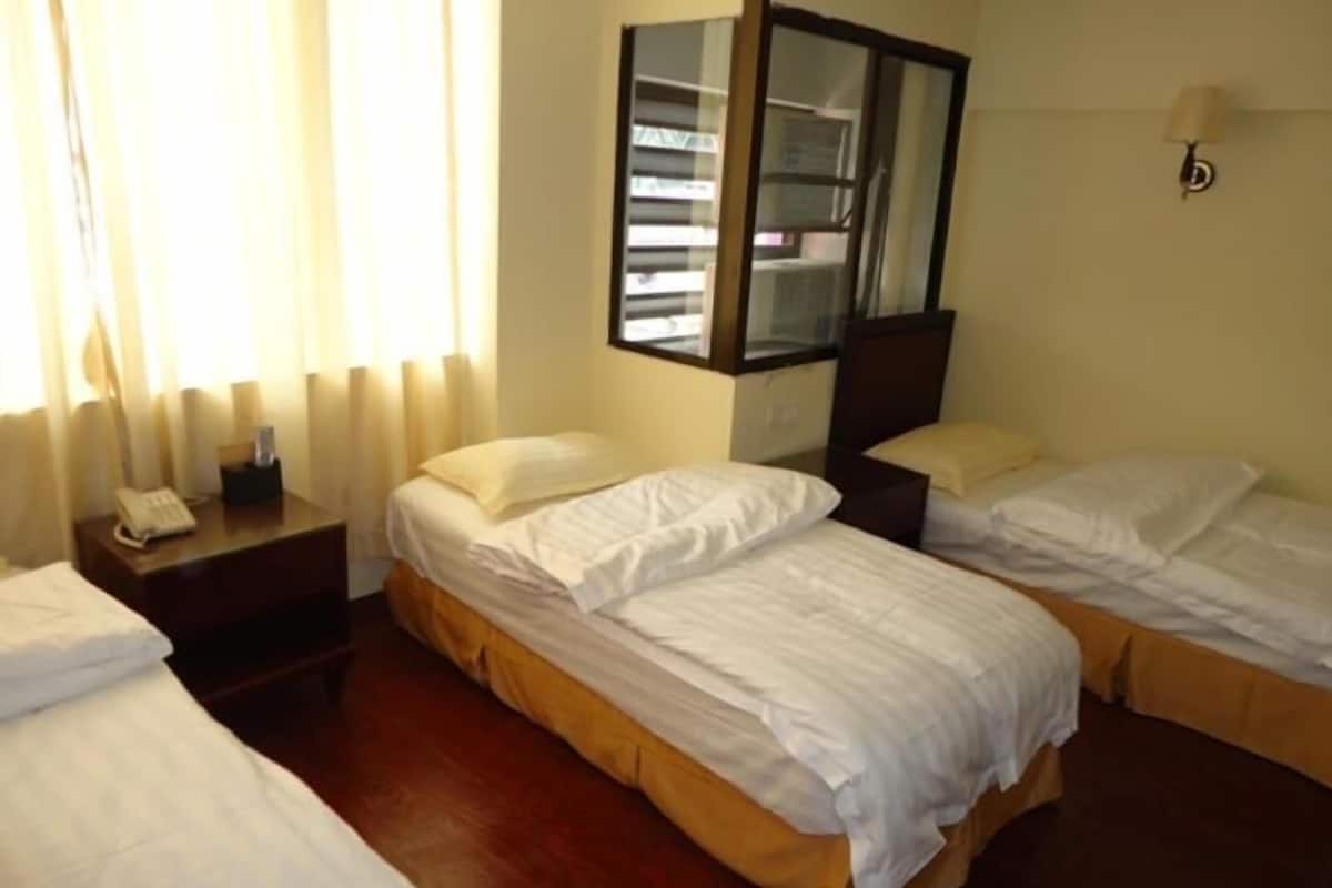 Habitación de hotel con dos camas, una mesita de noche con teléfono, un espejo y una ventana con cortinas.