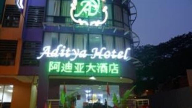 L’extérieur de l’hôtel Aditya, avec son enseigne au néon, son entrée surmontée d’un tapis rouge et des drapeaux.