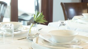 A neatly set dining table with white tablecloth, clear glassware, and a small potted plant. - Richtershuyz Guest House (Pretoria)