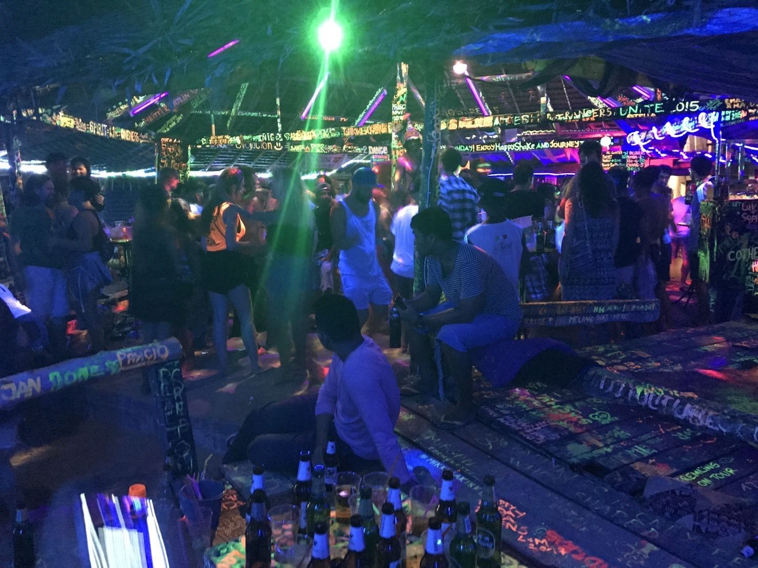 A crowded indoor venue with people standing and sitting around tables.