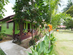 A green building with a porch and a small garden area with tropical plants and flowers. - Lanta Darawadee Resort (Ko Lanta)