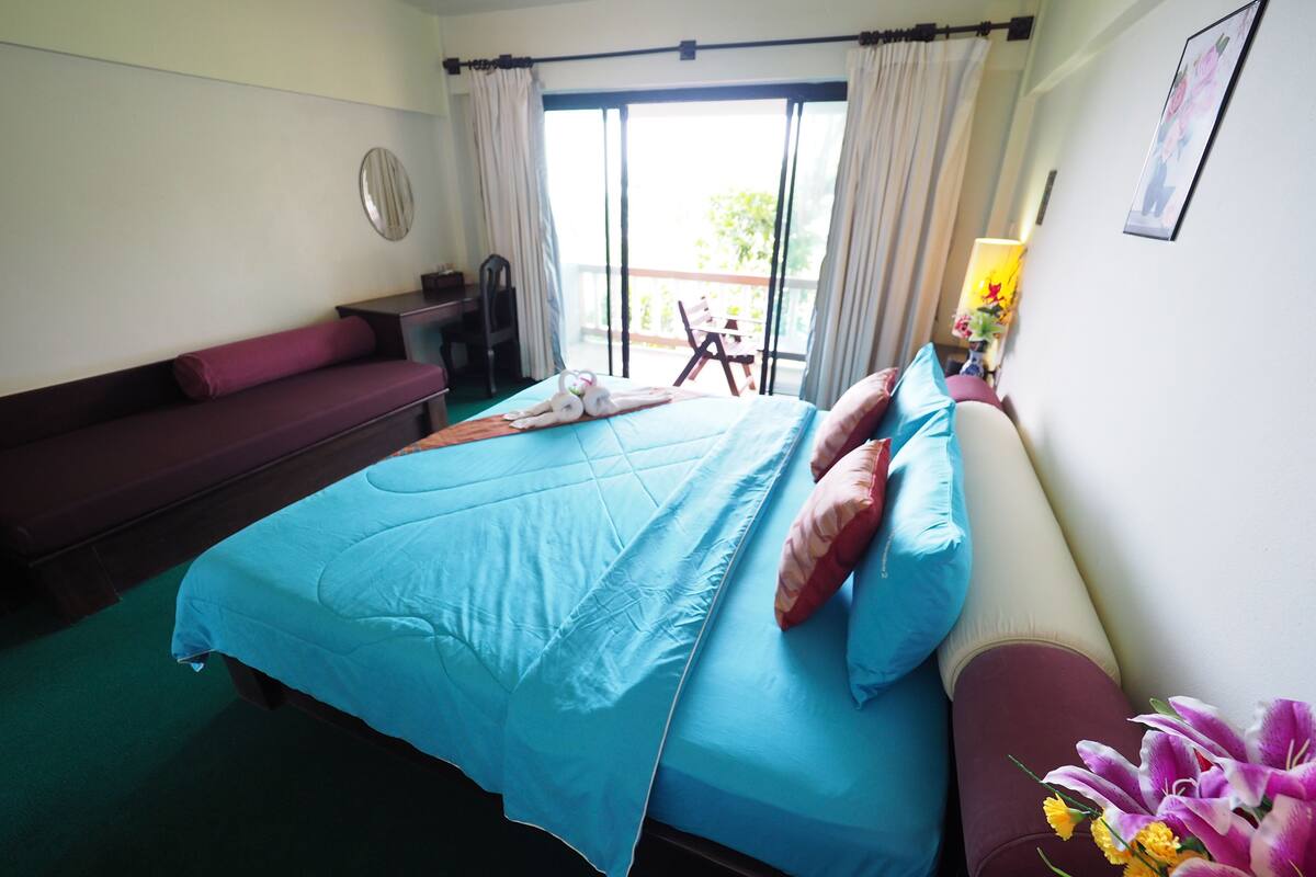 A hotel room with a bed, a sofa, a chair, and a small table.