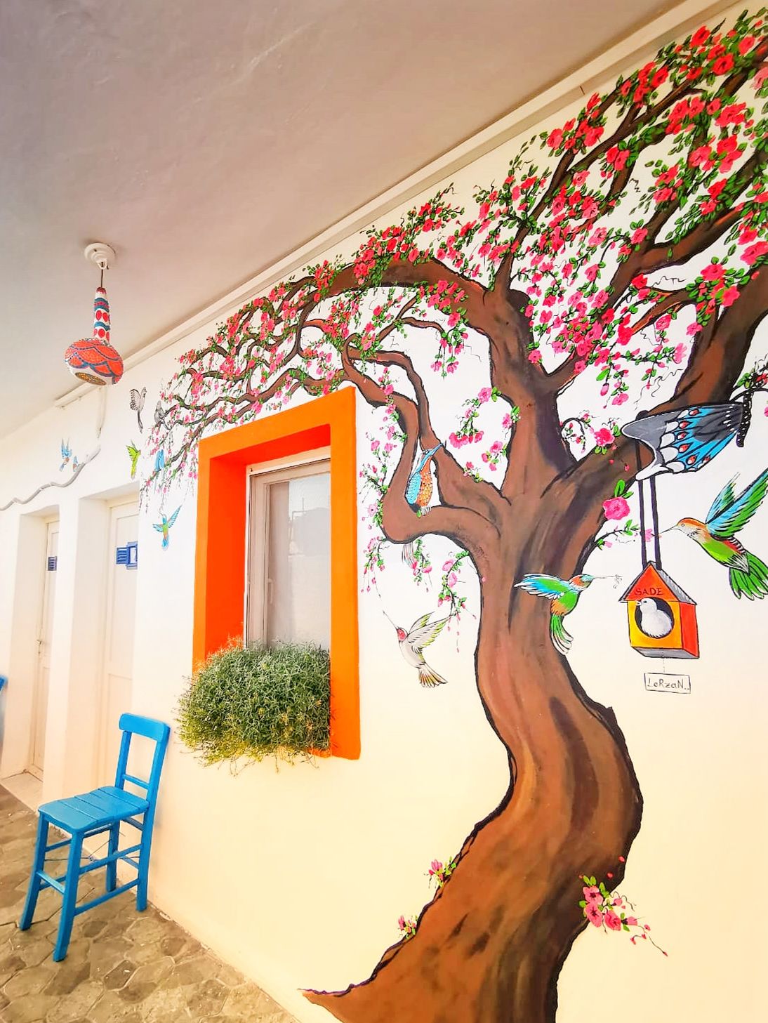 A mural of a tree with birds and flowers on a building wall.