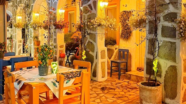 An outdoor patio area with stone walls, wooden furniture, and potted plants. - Sade Butik Otel (Bodrum)