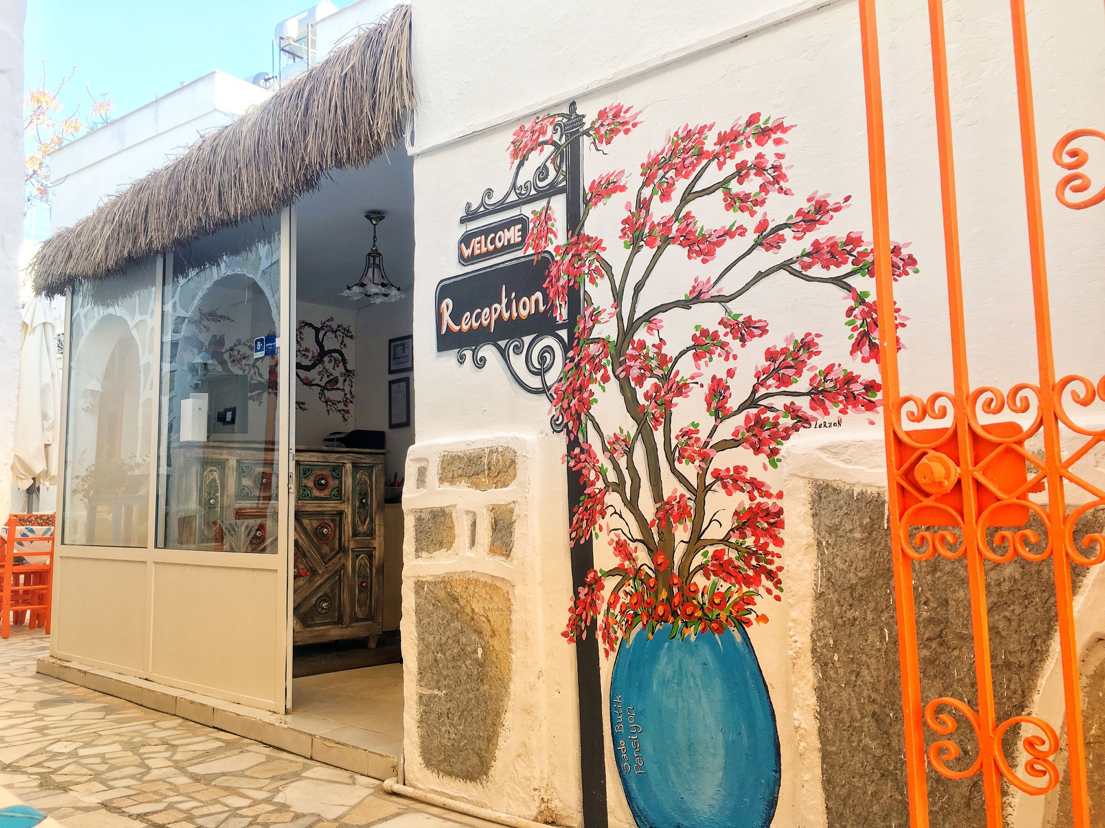 A building with a reception area, a blue vase with red flowers, and a sign that reads "Welcome Reception."