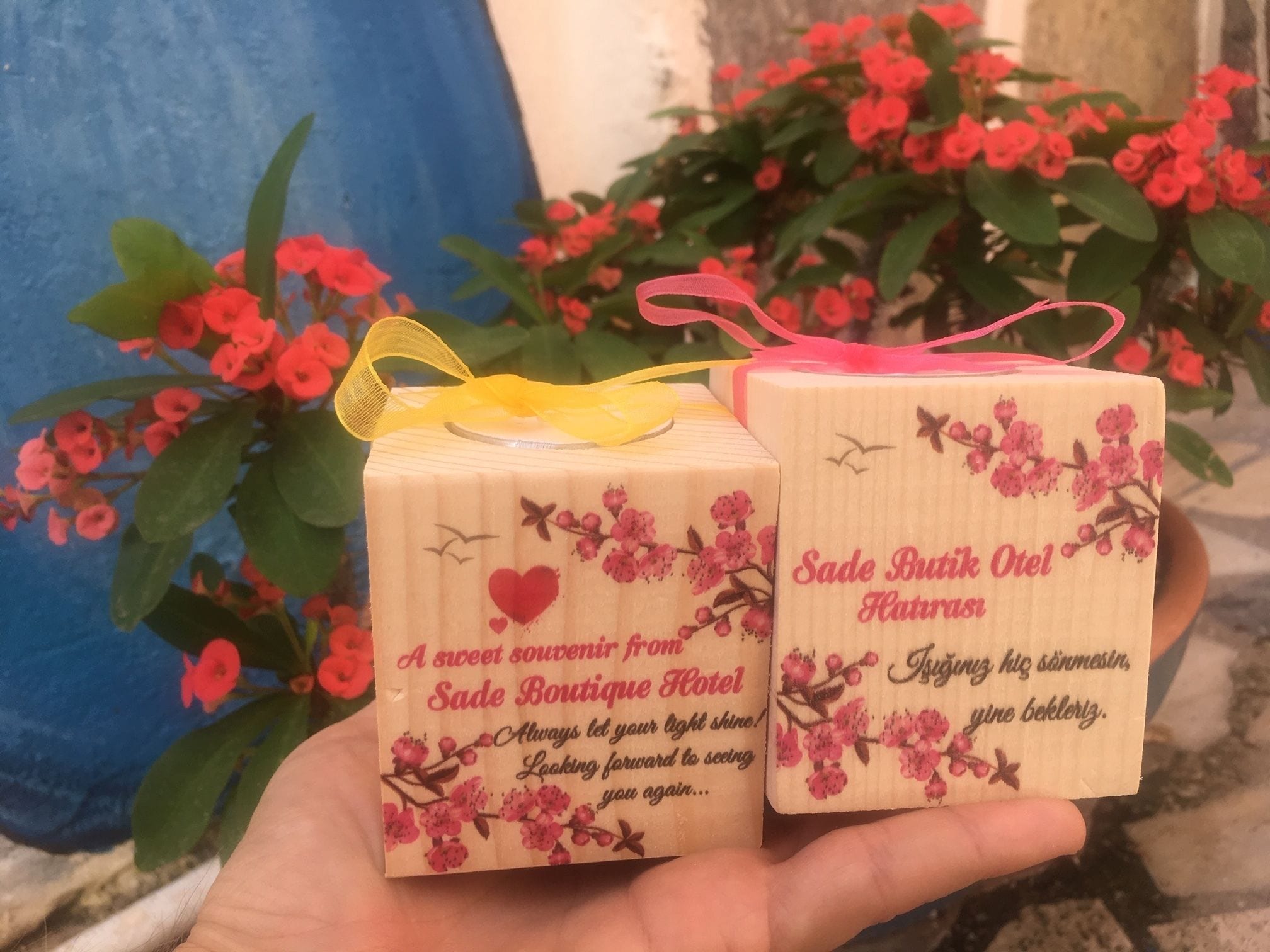 Deux petites boîtes en bois ornées de motifs floraux et de rubans, étiquetées comme souvenirs de l’hôtel Sade Boutique.