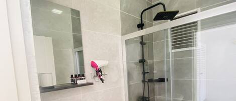 Un baño moderno con cabina de ducha de vidrio, lavamanos blanco y retrete.