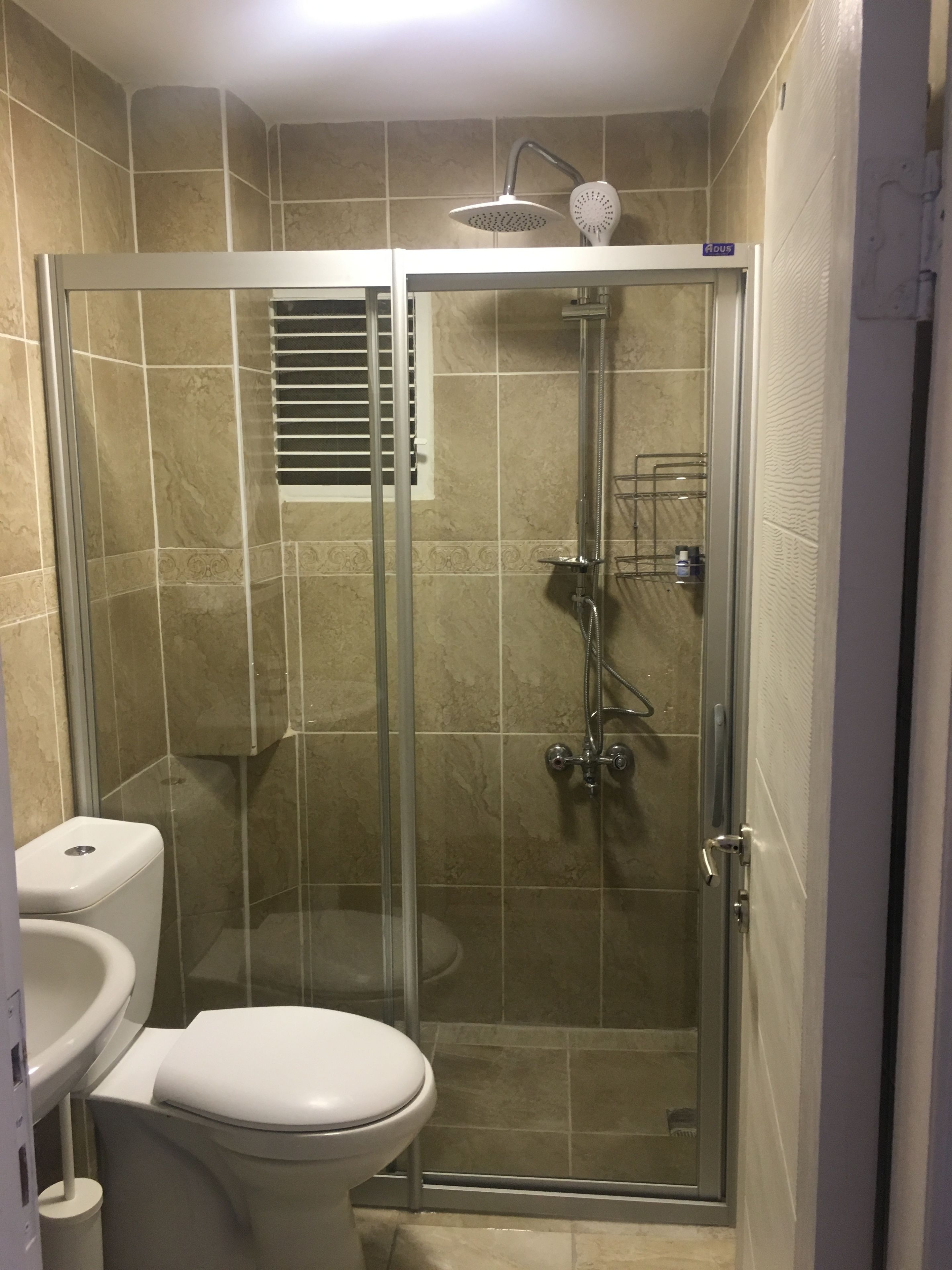 Eine Duschkabine mit Glaswänden, einer Handbrause und einem wandmontierten Wasserhahn.
