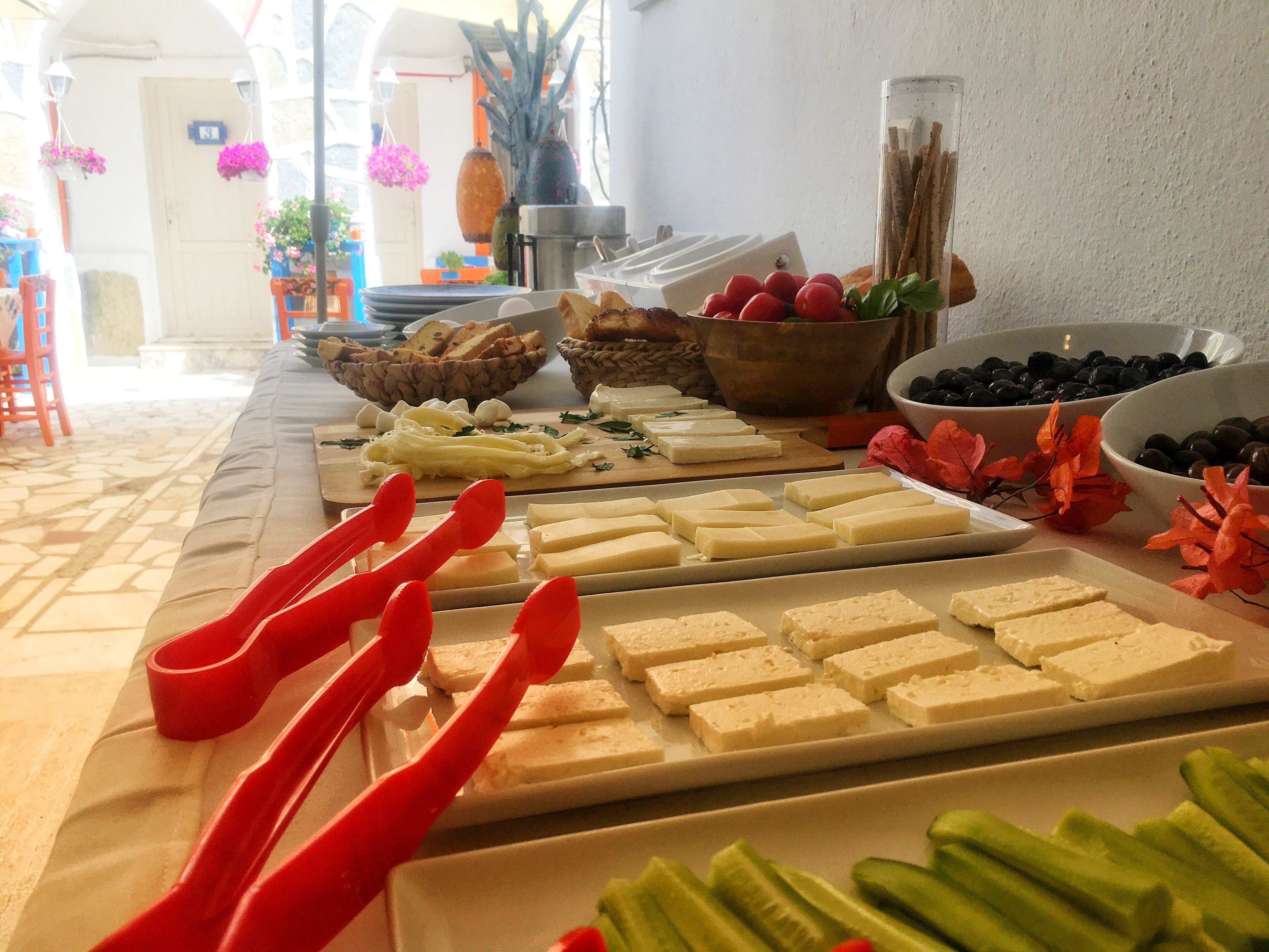 A buffet table with various cheeses, fruits, and vegetables.