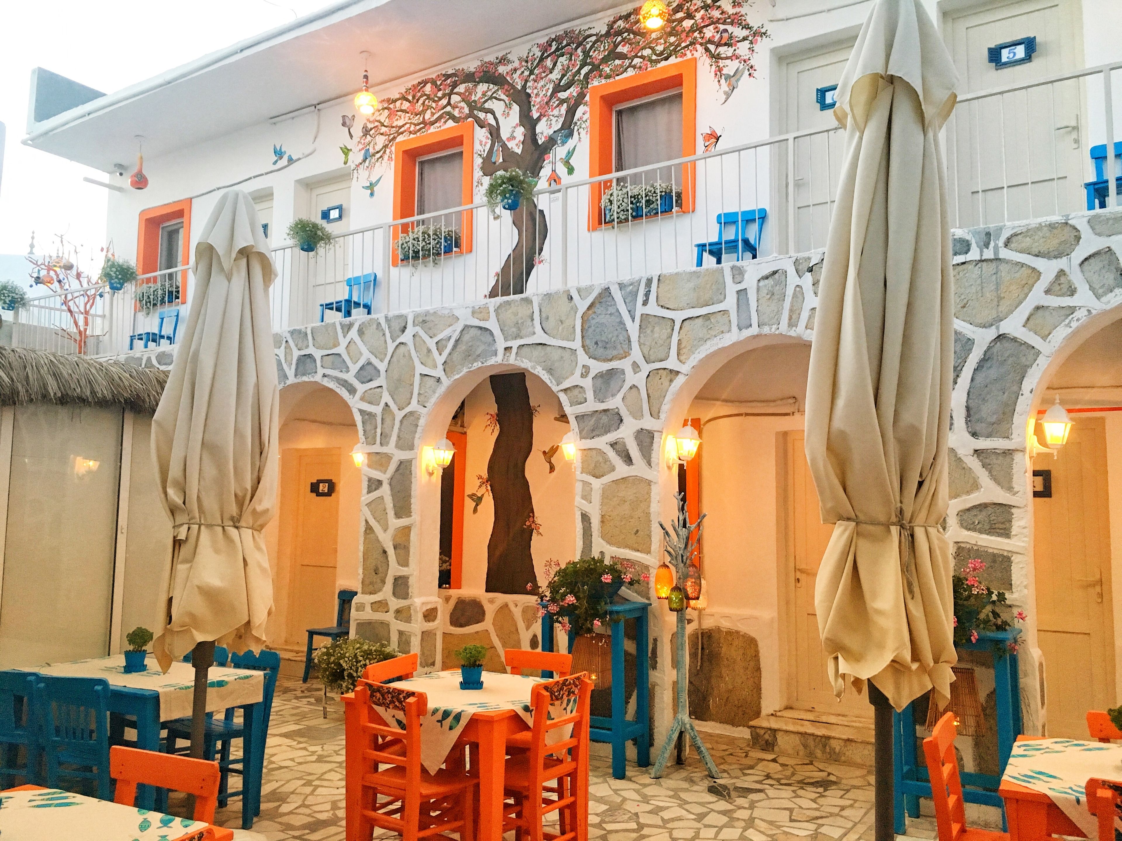 A restaurant with outdoor seating, stone arches, and colorful decor.