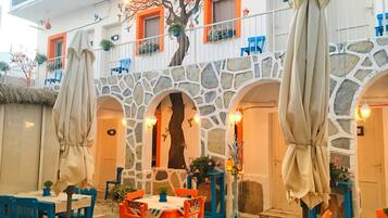 A restaurant with outdoor seating, stone arches, and colorful decor.