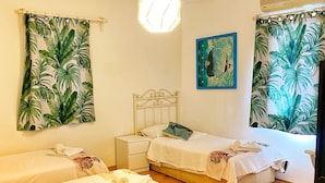 A room with two beds, a nightstand, a ceiling light, and tropical-themed curtains. - Sade Butik Otel (Bodrum)