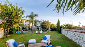 A backyard with a swimming pool, outdoor furniture, and a stone wall. - Alacati Casa Bella (Cesme)