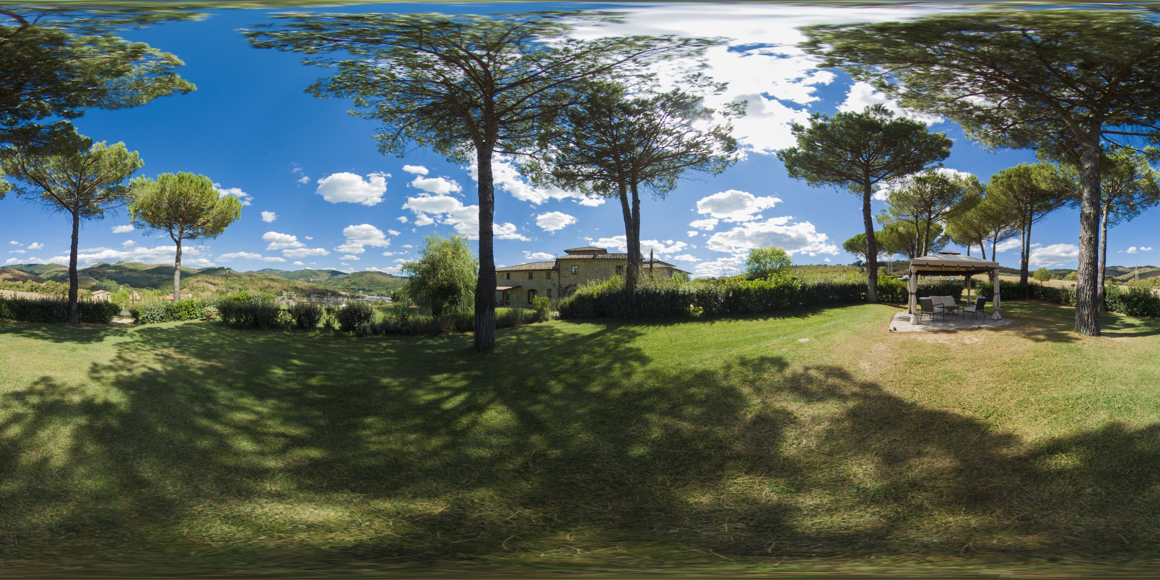 A serene landscape with a house surrounded by trees and a clear blue sky.
