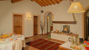 A dining area with a table set for a meal, a fireplace, and a wooden ceiling. - Cavarchino B&B (Gaiole in Chianti)