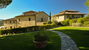 A stone building with a tiled roof, a stone pathway, and a well-maintained lawn. - Cavarchino B&B (Gaiole in Chianti)