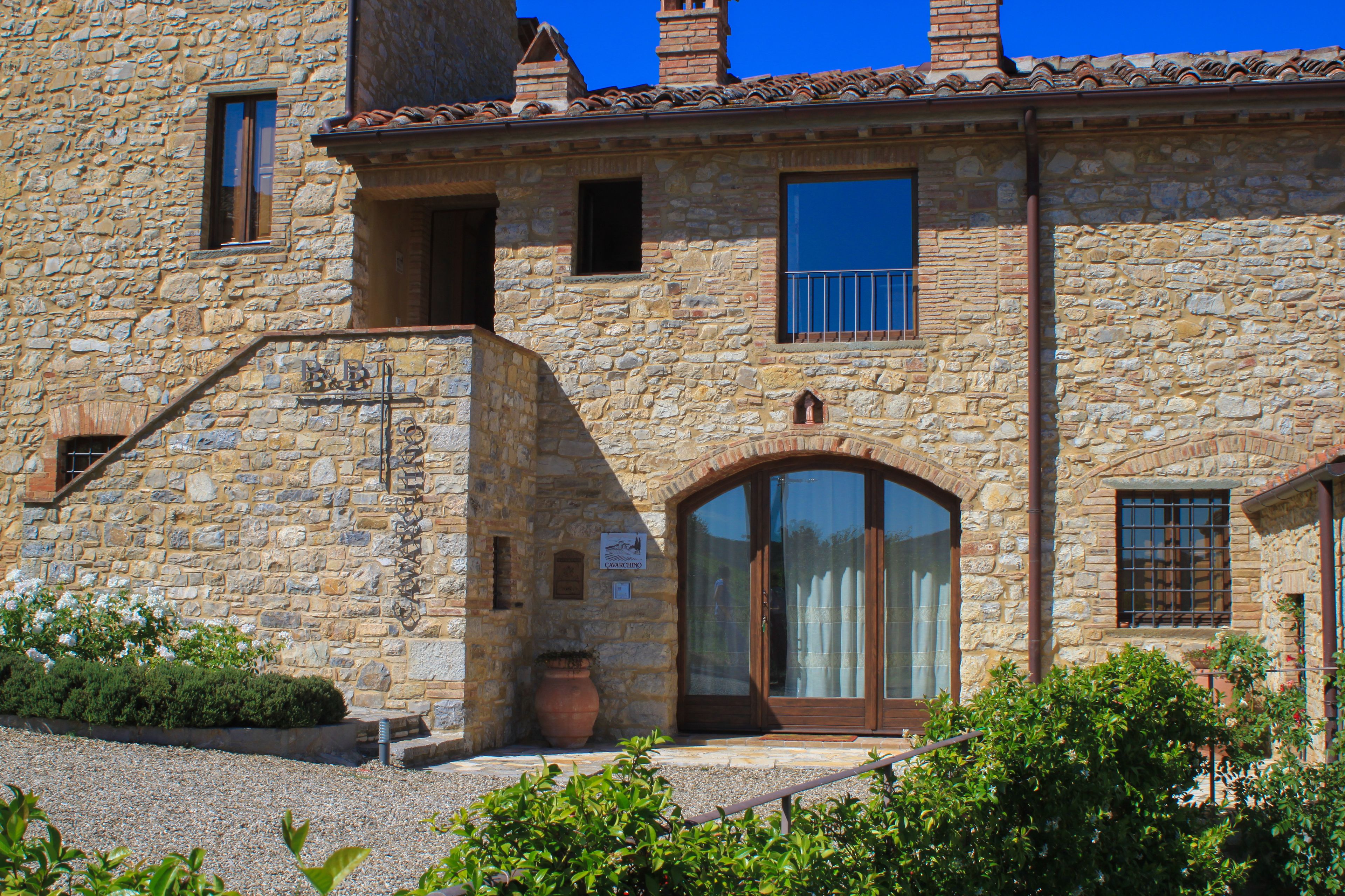 Ein Steinhaus mit großem Bogenportal, einem kleinen Balkon und einem Blumentopf.