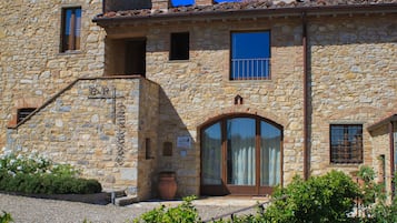 Ein Steinhaus mit großem Bogenportal, einem kleinen Balkon und einem Blumentopf.