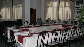 Un comedor con mesas dispuestas para una comida, sillas y una araña.