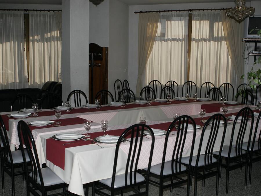 Un comedor con mesas dispuestas para una comida, sillas y una araña.