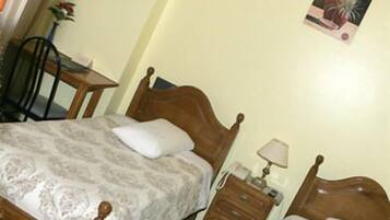 A bedroom with a wooden bed, a bedside table, a lamp, and a chair.