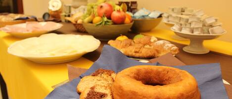 A table with various food items including a donut, bread, and a bowl of fruit.