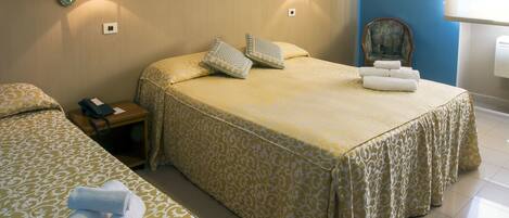 Une chambre d’hôtel avec deux lits, chacun recouvert d’une couvre-lit à motifs, une table de chevet avec une lampe et un téléphone.