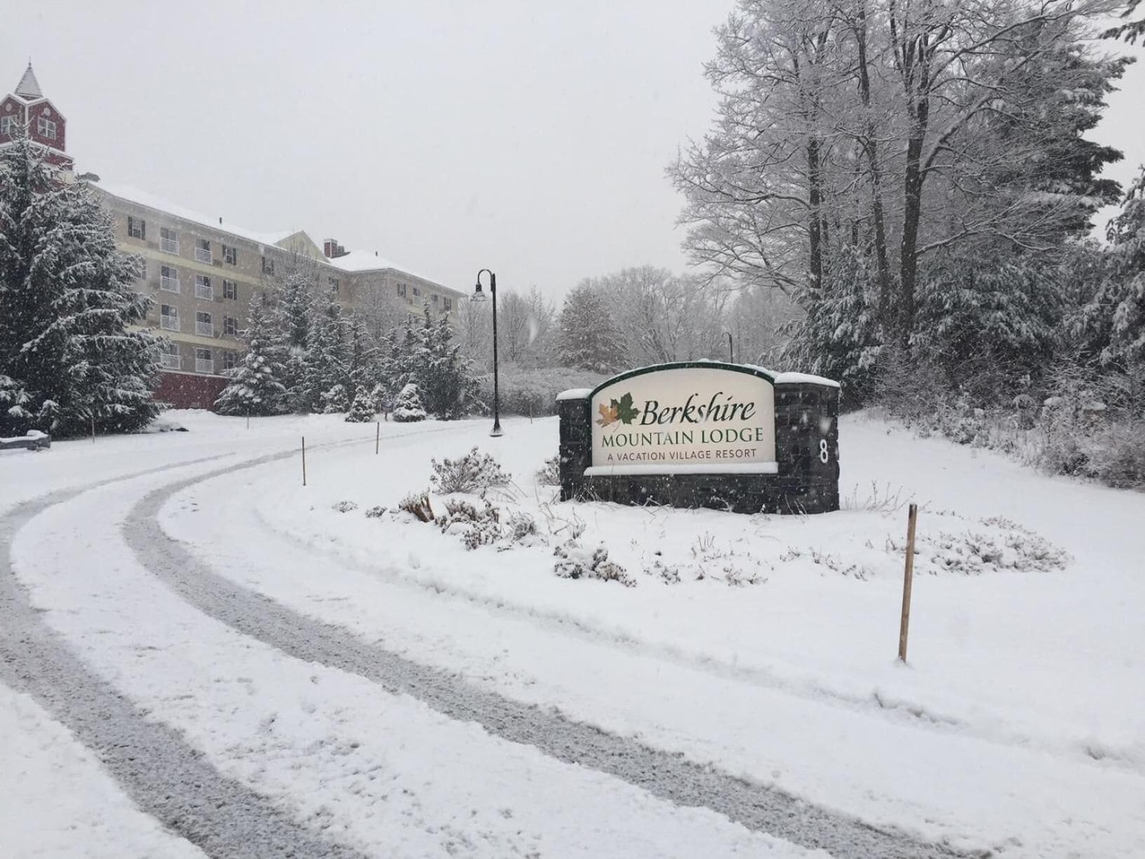 A snow-covered road leading to a sign for Berkshire Mountain Lodge, a vacation village resort.