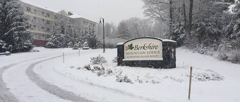 A snow-covered road leading to a sign for Berkshire Mountain Lodge, a vacation village resort.