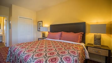 A neatly made bed with a patterned bedspread, a bedside lamp, and a nightstand with a drawer.