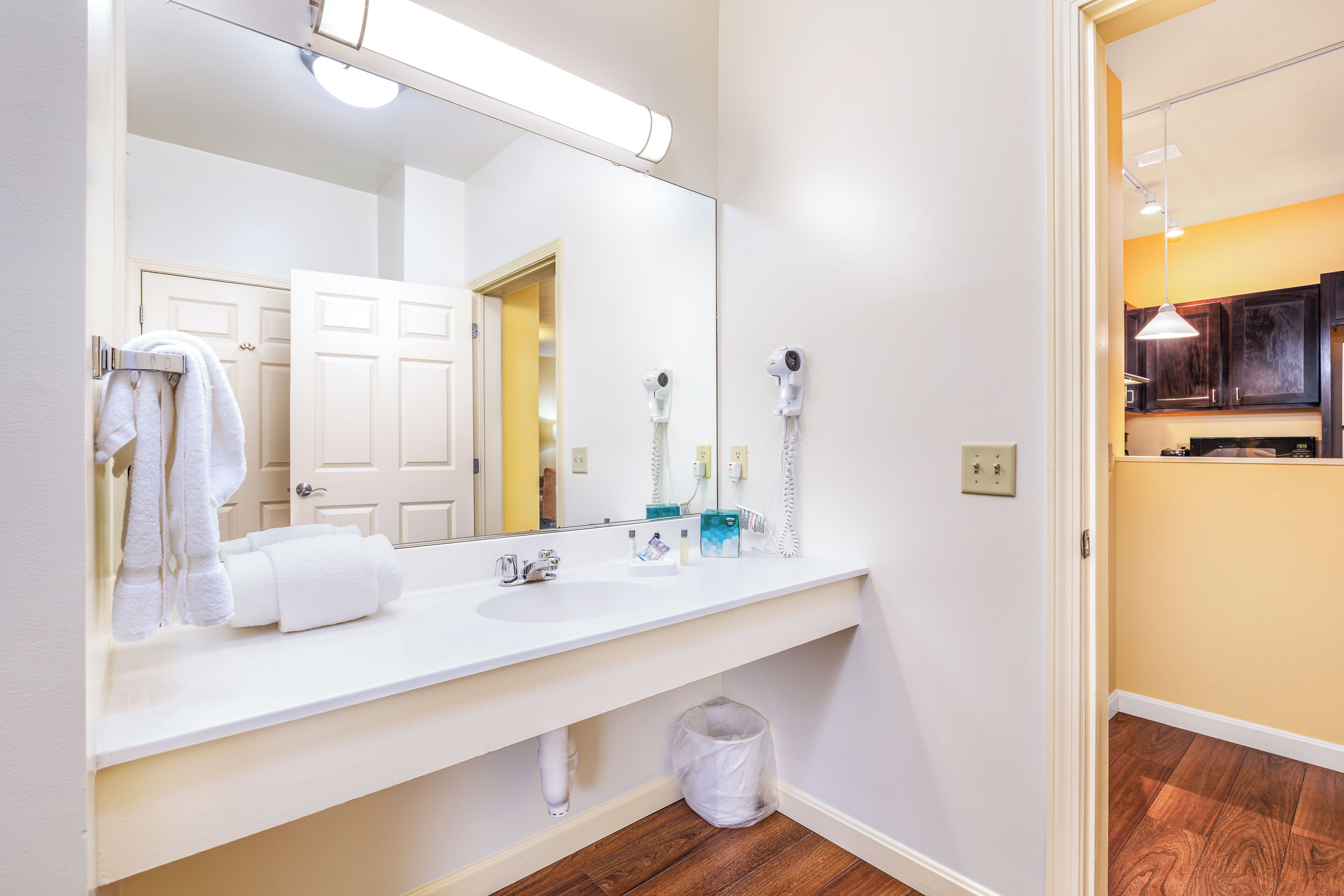 Une salle de bain avec un lavabo blanc, un grand miroir et un porte-serviettes.