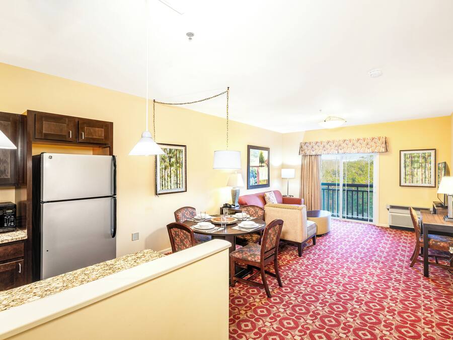 A compact hotel room with a kitchenette, a dining area, and a living space.