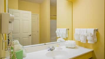 A bathroom with a white sink, a mirror, and white towels hanging on the wall.