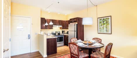 Una cocina compacta con muebles de madera, un refrigerador y un comedor con mesa y sillas.