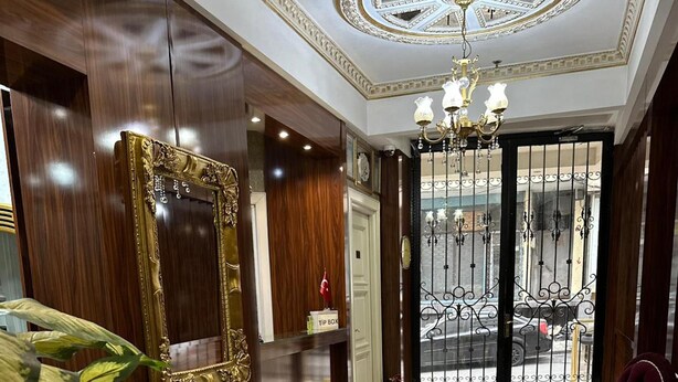 A hotel lobby with marble flooring, a reception desk, a large mirror, and a chandelier. - Sahra Airport Hotel (Istanbul)