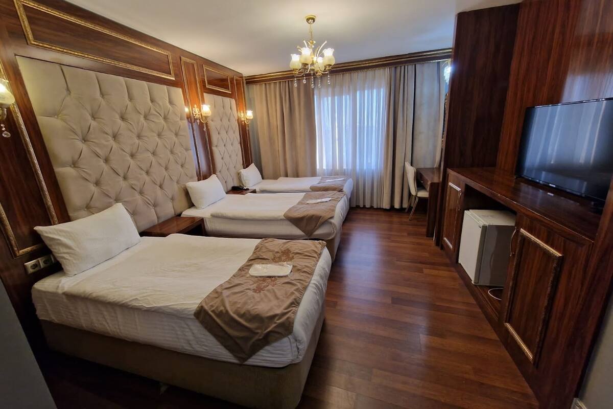 Une chambre d’hôtel avec trois lits, une télévision et un minibar.