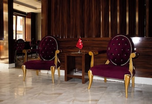 A hotel lobby with marble flooring, two upholstered chairs with gold legs, and a small table with a flag. - Sahra Airport Hotel (Istanbul)