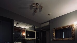 A hotel room with a large bed, a television, a mirror, and a desk with a chair. - Sahra Airport Hotel (Istanbul)