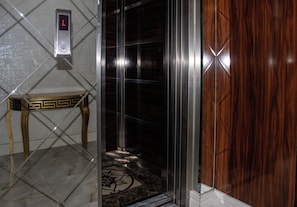 An elevator with a digital display, a marble floor, and a wooden panel on the right. - Sahra Airport Hotel (Istanbul)