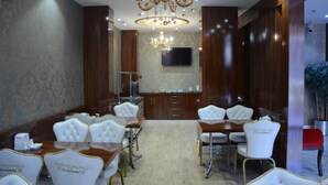 A formal dining room with a chandelier, wooden paneling, and a flat-screen TV on the wall. - Sahra Airport Hotel (Istanbul)