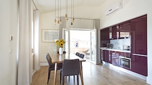 A modern kitchen with a dining area, featuring a wooden dining table, chairs, and a pendant light. - Casa di Bava Suites by TCH (Istanbul)