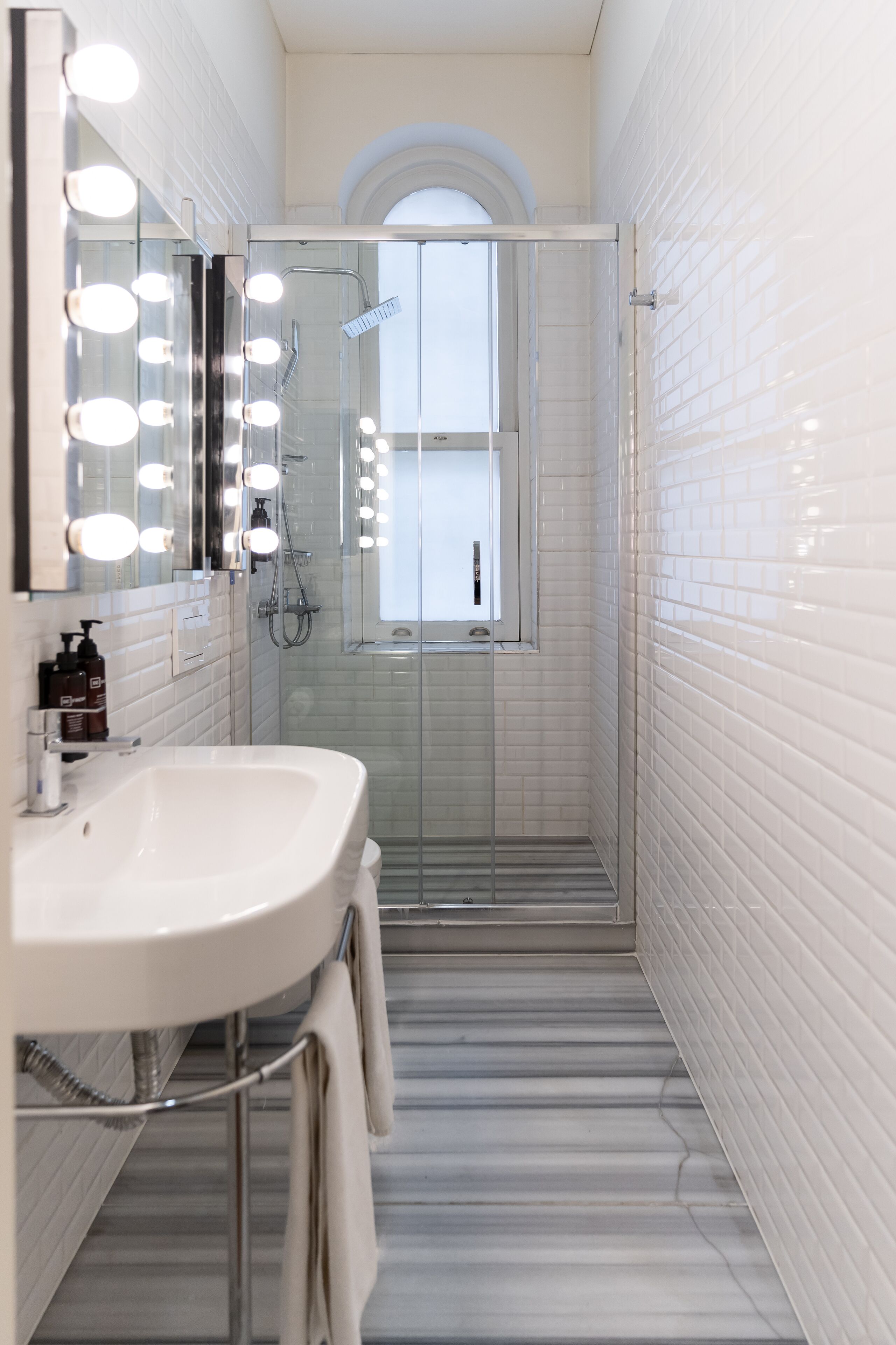 A modern bathroom with a white sink, vanity mirrors, and a glass-enclosed shower.