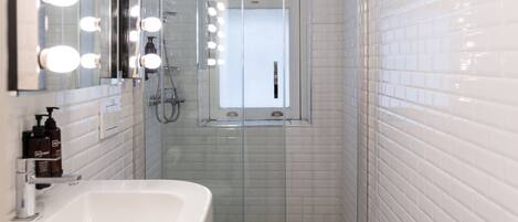 A modern bathroom with a white sink, vanity mirrors, and a glass-enclosed shower.