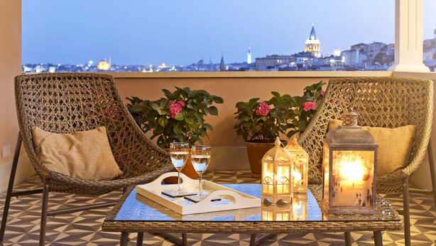 A balcony with wicker chairs, a tray table with drinks, a lantern, and potted plants. - Casa di Bava Suites by TCH (Istanbul)