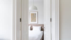 A hallway leading to a bedroom with a bed, a hanging light fixture, and a framed artwork on the wall. - Casa di Bava Suites by TCH (Istanbul)