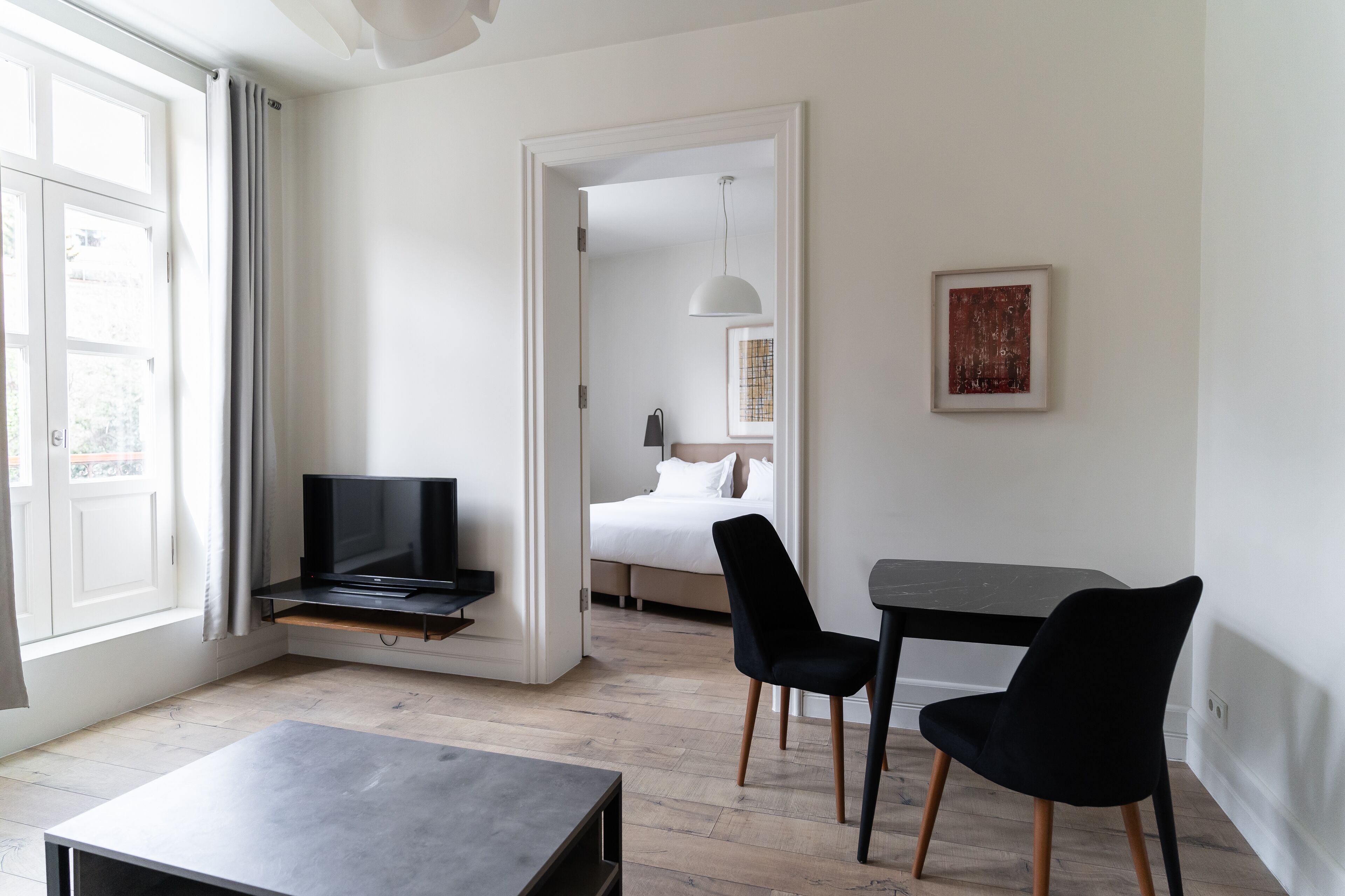 Quarto de hotel moderno com cama, televisão, escrivaninha e cadeira.