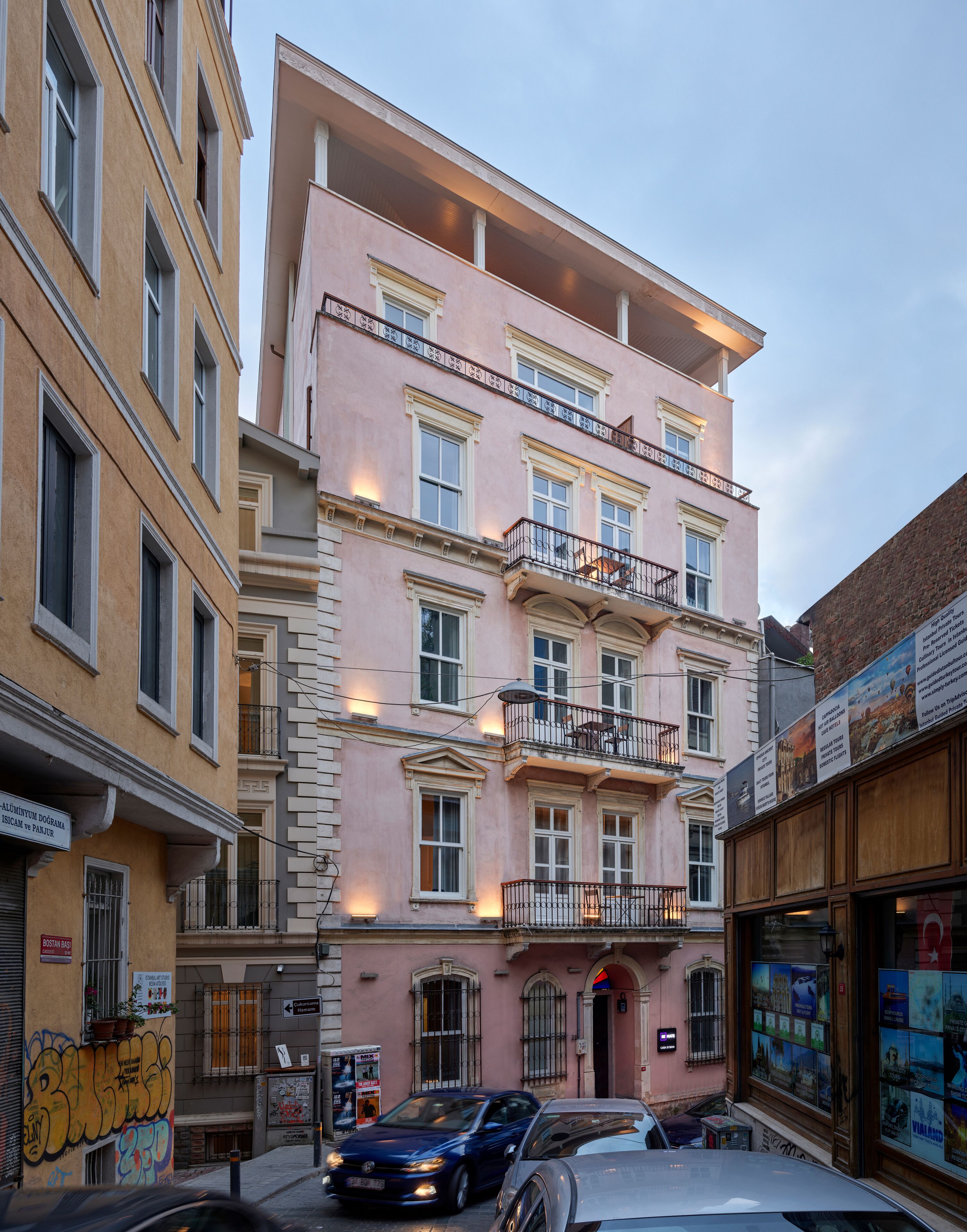 Um edifício de vários andares com varandas, entrada visível e vista para a rua.