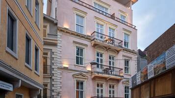 Um edifício de vários andares com varandas, entrada visível e vista para a rua.